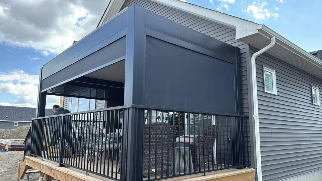 Black louvered pergola with retractable privacy screens on a deck
