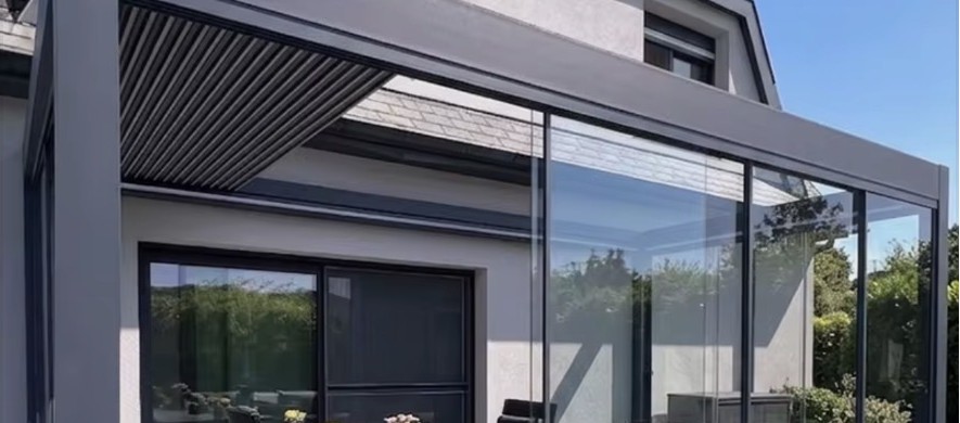 Louvered pergola with sliding glass enclosure against a modern home